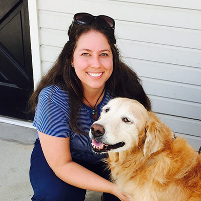 a woman holding a dog posing for the camera