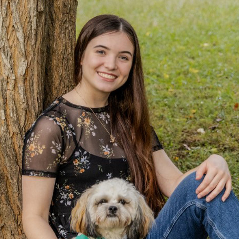 a woman holding a dog posing for the camera