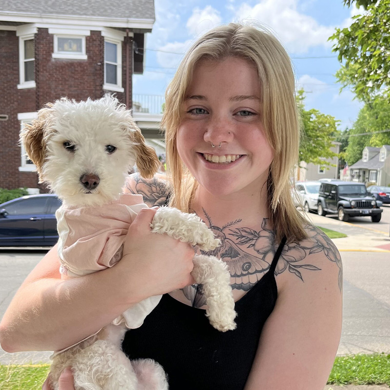 a woman holding a dog posing for the camera