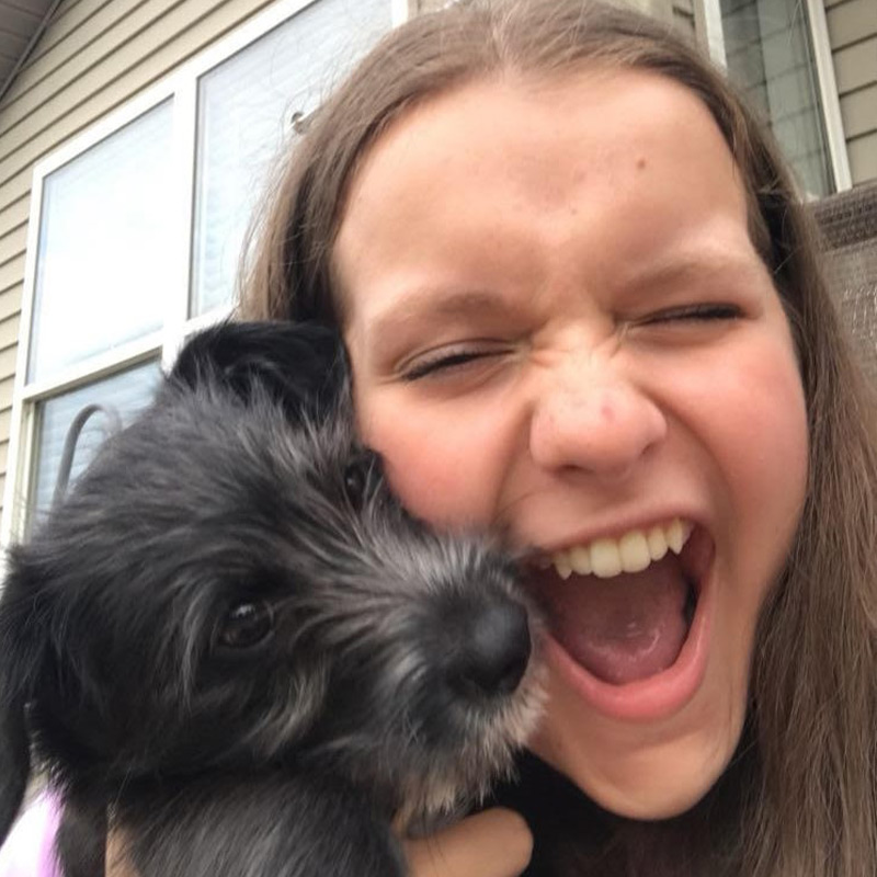 a woman holding a dog posing for the camera