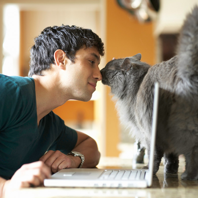 a man standing next to a cat