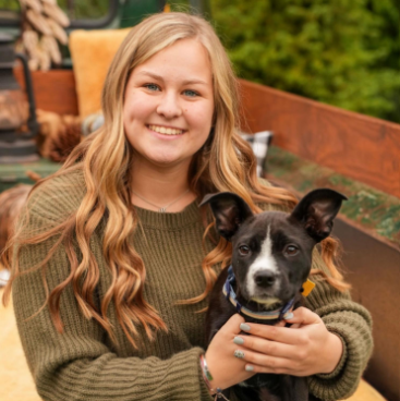 a woman holding a dog posing for the camera